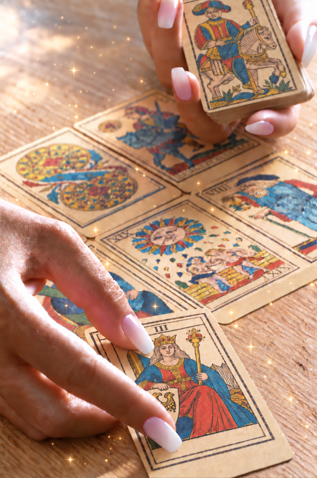 Mains aux ongles ombrés présentant L’Impératrice du Tarot de Marseille dans une lumière scintillante